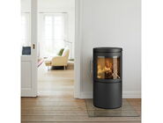 Schwarzer Kaminofen mit brennendem Feuer in hellem Wohnzimmer